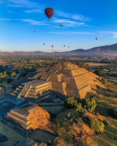 several hot air balloons flying over an ancient structure