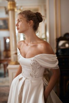 a woman in a white wedding dress posing for the camera with her hands on her hips