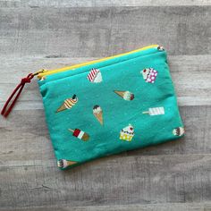 Lined zippered pouch, approximately 6.25" x 4.5". Due to being a handmade item, measurements may slightly vary. Adorable prints, inside and out. A padded lining makes this zippered pouch perfect for whatever you need a zippered pouch for! Great for traveling to organize ALL THE THINGS. Add a gift card (or two) and some travel size luxury beauty products for a great little gift! Exterior and interior fabrics are 100% cotton. YKK zipper and polyester batting also used. Spot clean only.  Ice cream treat pattern on turquoise background. Yellow zipper and red faux-suede zipper pull. Black and white polka dot interior print.  All items are handmade in my smoke-free home. Ships in a poly mailer to reduce shipping costs. Luxury Beauty Products, Ice Cream Treats, Turquoise Background, Poly Mailer, Zippered Pouch, Ykk Zipper, Interior Fabric, Purse Pouch, Gift Card Holder