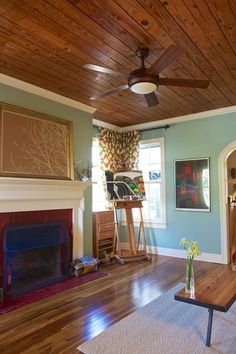 a living room filled with furniture and a painting easel on the wall next to a fire place