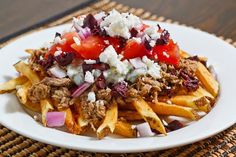 a white plate topped with french fries covered in toppings