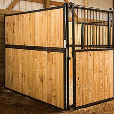 a wooden fence with metal bars on the top and bottom part, in front of a barn