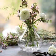 a vase filled with white flowers sitting on top of a table next to some scissors