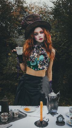 a woman with red hair and makeup holding a cup