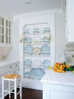 a white kitchen with blue and yellow dishes on shelves