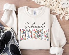 Matching T-Shirt: https://www.etsy.com/listing/1711494066/school-nurse-shirt-school-nurse-t-shirt?click_key=effbbf4bcb5eaf9d6db9f574d76c552e103cf21e%3A1711494066&click_sum=37da5a96&ref=shop_home_active_1&pro=1&sts=1 Unisex heavy blend crewneck sweatshirt. Our sweatshirts are Gildan brand. Please check the size chart before ordering and choose the desired color. All of our sweatshirts are UNISEX. FABRICATION: Unisex Gildan Sweatshirt: 50% cotton, 50% polyester CARE INSTRUCTION: Turn inside out an School Nurse Outfits Elementary, School Nurse Shirts Ideas, School Nurse Shirt, Nicu Nurse Education, Nurse Organization, School Nurse Office, Nursing Information, Nurse Sweater, Nurse Crewneck