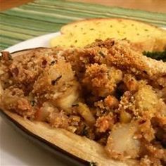 a white plate topped with bread and meat next to broccoli on a table