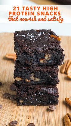 three chocolate brownies stacked on top of each other with pecans scattered around them