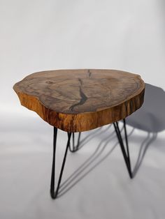 a wooden table with black hairpin legs sitting on top of a white floor next to a gray wall