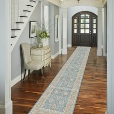 a long hallway leading to a foyer with wooden floors and white trim on the walls