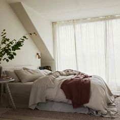 an unmade bed sitting in front of a window