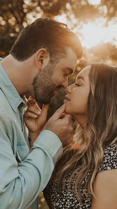 a man and woman standing next to each other in front of the sun with their noses close together