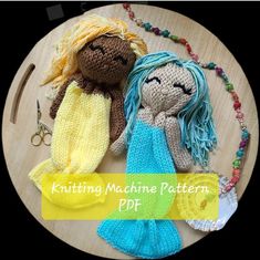 two knitted mermaid dolls sitting next to each other on top of a wooden table