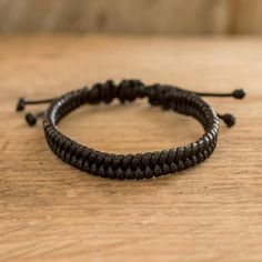 a black string bracelet on top of a wooden table