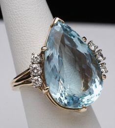 Pear Cut Blue Topaz with Side Diamond Flair Ring 14K Yellow Gold Size US 5 1/4 Weight: 13.4 grams Blue Topaz measures approx 23 mm tall x 14.8mm wide (approx 21.8ct) Topaz is approximately VS quality Round Diamonds: approx 1/2 cttw Diamond Color: approx H-I Diamond Clarity: approx VS2-SI1 Head of Ring measures approx 22 mm wide x 25.8mm tall This is a pre-owned item in Good Condition. It does show signs of use/wear but there is still lots of life left to this ring. Topaz has some chips at the fa Ring Cat, Gold Statement Ring, Diamond Color, Pear Cut, Diamond Clarity, Statement Ring, Rings Statement, Blue Topaz, Colored Diamonds