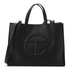 This is an authentic TELFAR Vegan Leather Medium Shopping Bag in Black.This is a tote crafted of synthetic leather in black with the iconic raised Telfar logo at the front. The shoulder bag has short top handles, and two long shoulder straps. The top secures with a magnet snap and opens toa black fabric-lined interior with a zippered pocket. Telfar Tote Bag, Telfar Logo, Medium Bags, Black Tote Bag, Synthetic Leather, Black Fabric, Short Tops, Shoulder Straps, Vegan Leather