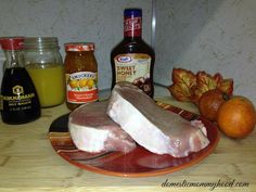 two pieces of meat sitting on top of a plate next to oranges and honey