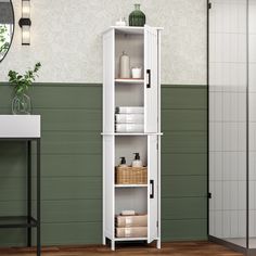 a tall white cabinet sitting on top of a hard wood floor next to a green wall