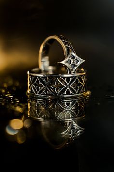 two wedding rings sitting on top of a table next to each other with reflections in the water