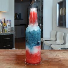 a red, white and blue bottle sitting on top of a wooden table in a kitchen