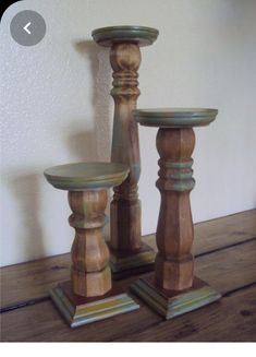 three wooden candlesticks sitting on top of a wooden table next to a wall