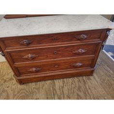 an old dresser with marble top and wooden handles on the bottom, sitting on a hard wood floor