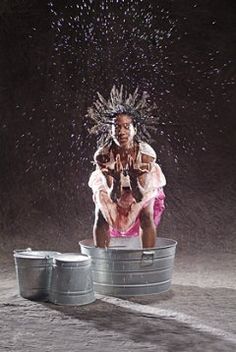 two women are sitting on top of barrels in the rain and splashing water all over them