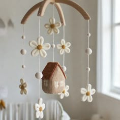 a crocheted birdhouse hanging from a tree branch with white flowers on it