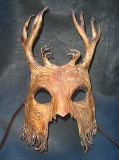 a wooden mask with horns and eyes on a blue background