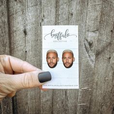 a person holding up a business card with two men's faces on it,