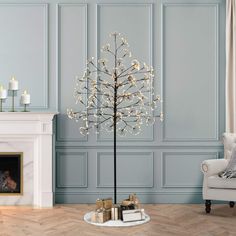 a living room with blue walls and a white tree in the center, surrounded by candles