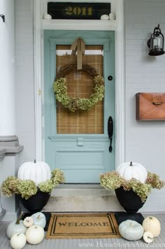 the front door is decorated with wreaths and pumpkins