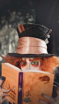 a woman with red hair and green eyes is reading a book while wearing a hat