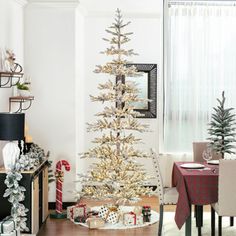 a white christmas tree in a living room next to a table with presents on it