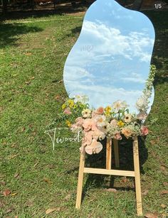 a large mirror sitting on top of a wooden easel in the middle of a field