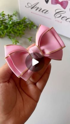 the pink bow is being held up by someone's hand