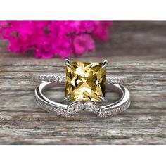 a yellow diamond ring on top of a wooden table with pink flowers in the background