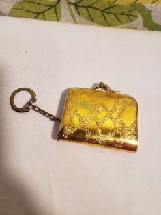 a gold colored pocket watch sitting on top of a white cloth covered table next to a keychain