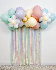 a bunch of balloons that are on top of a wall next to a curtain with streamers