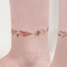 a woman's foot with flowers and leaves tattooed on the side of her leg