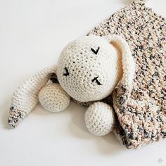 a crocheted stuffed animal laying on top of a white table next to a blanket