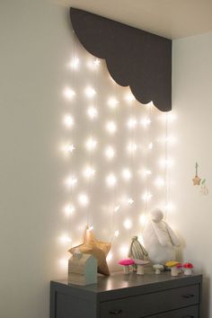 a white wall with some lights on it and a black dresser in front of it