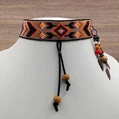 This choker has a folded leather strip with wooden beads dangling from the center to give it a bolo tie look. The choker's pattern has a diamond center with floral patterns shooting out. Next are chevrons and diamond shapes throughout the rest of the choker. It comes with free 3 strand earrings that have antique copper feathers and beads. Bohemian Lariat Choker With Adjustable Length, Bohemian Adjustable Lariat Choker, Adjustable Bohemian Lariat Choker, Bohemian Lariat Choker For Festivals, Adjustable Beaded Brown Choker, Adjustable Cord Choker For Festival, Adjustable Brown Beaded Choker, Bohemian Adjustable Choker, Traditional Adjustable Beaded Choker Necklace