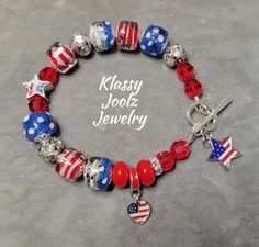 This lovely Patriotic Bracelet is made with beautiful and unique Artisan Lampwork Beads.  Perfect for the 4th of July, Memorial Day, or any Patriotic Occasion.  Another "One of a Kind" jewelry creation by Klassy Joolz. *  Artisan Patriotic Lampwork Barrel Shaped Beads - Art Beads *  Artisan Lampwork Rondelle Spacer Beads - Art Beads *  Swarovski Crystals *  Star Enamel Charm Dangle *  Star Enamel Focal Bead *  Heart/Flag Dangle Charm *  Silver Beads, Bead Caps and Crystal/Rhinestone Rondell Spac Patriotic Colorful Beads Bracelet For Gift, Patriotic Beaded Bracelets With Colorful Beads As Gift, Patriotic Beaded Bracelets For Gifts, Handmade Patriotic Multicolor Beaded Bracelets, Patriotic Round Beads Jewelry Gift, Handmade Adjustable Patriotic Bracelets, Patriotic Jewelry With Colorful Beads As Gift, Handmade Adjustable Patriotic Bracelet, Patriotic Handmade Adjustable Bracelets