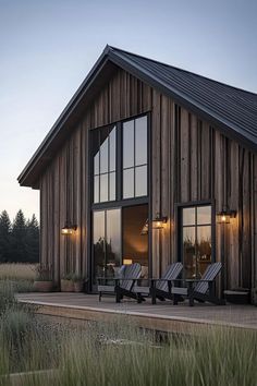 two chaise lounges in front of a wooden building with large windows at dusk