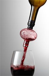 a wine glass filled with red wine being poured into it by a corkscrew