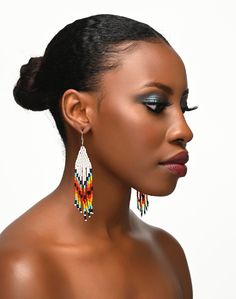 Add a touch of African tribal style to your look with these stunning tassel, beaded, and dangle/drop earrings. Perfect for women who love to accessorize with unique and eye-catching pieces, these earrings are made from high-quality beads and feature a beautiful white and multicolor design. They are ideal for those who love ethnic and regional jewellery.  Length:8.5cm Width:2.5cm Weight:6g Length:8.5cm Width:2.5cm Weight:6g Festival Earrings, African Earrings, Traditional Earrings, Turban Headwrap, Ethnic Earrings, Maasai, African Jewelry, Colorful Earrings, Wooden Earrings