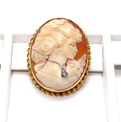 14k Yellow Gold Cameo Diamond Brooch pendantBeautiful detailed carving on her hair and flowers on her dressClasp and pendant hoop in good working conditionStamped: "14k" inside of the rimMeasures approx. 1 1/2" long X 1 1/4" wide or 3.9 cm X 3 cmOutside rim measures approx. 2 mm wide - Twisted ropeDiamond is approx: .02 ctTotal weight: 8.1 gFEEL FREE TO MESSAGE ME WITH A BEST OFFER!041315-4070Please contact me if you are interested in purchasing multiple items, I am happy to negotiate and accomm Elegant Carved Gold Brooches, Carved Yellow Gold Brooches For Wedding, Carved Brooches For Formal Occasions, Elegant Yellow Gold Intaglio Brooches, Elegant Yellow Gold Brooches With Intaglio, Elegant Yellow Gold Intaglio Brooch, Cameo Brooches For Wedding, Anniversary Oval Brooches, Formal Engraved Brooches