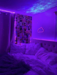 a bed in a room with purple lights on the wall and pictures hanging above it