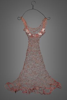 a dress hanging on a clothes hanger in front of a gray background with red and white lines